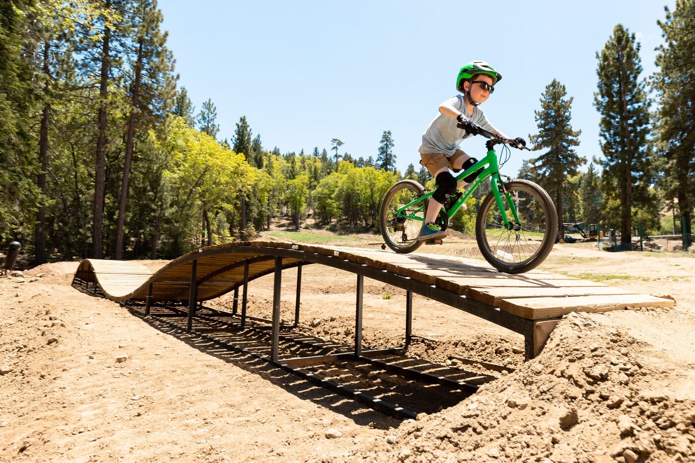 Young rider clearing a wooden feature on a mountain bike